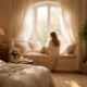 Woman sitting on a window seat in a softly lit bedroom, surrounded by neutral decor and natural light.